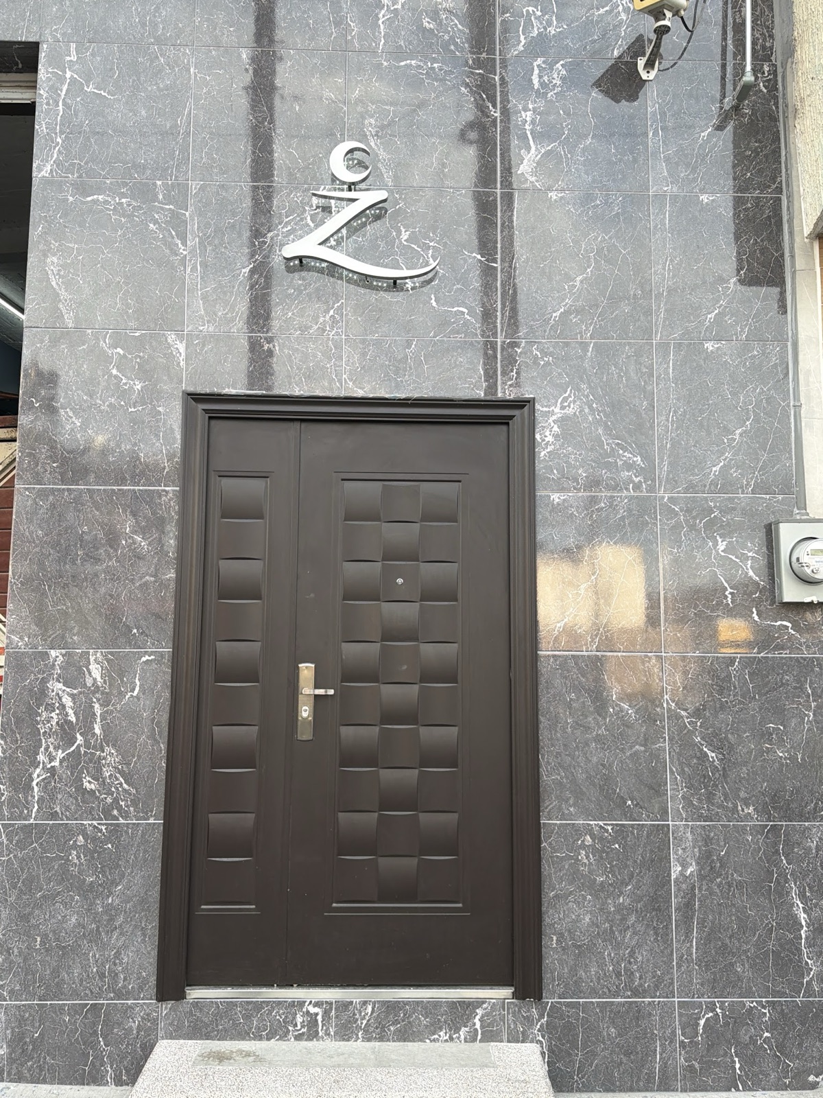Puerta de acceso a Zenvara Activa con el isotipo en acero sobre mármol gris